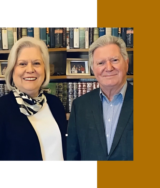 Two people smiling, standing in front of a bookshelf filled with books on hypnosis therapy.