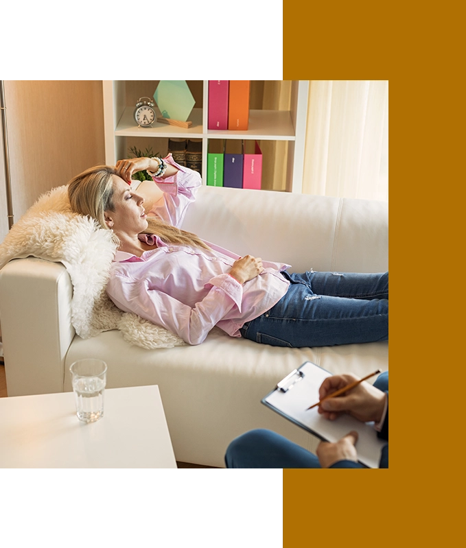 A person reclines on a sofa in a living room, arm resting on their forehead, as they meditate on their journey with hypnosis for depression. A glass of water and a clipboard are nearby.