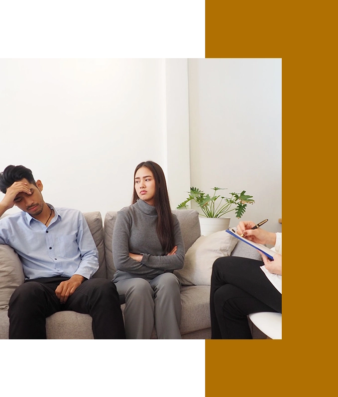 In a counseling session, a man appears frustrated while a woman sits with crossed arms. Nearby, another person holds a clipboard, perhaps considering the benefits of Hypnosis Services in Hartsville to help guide the discussion.