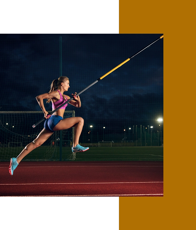 A woman in athletic wear pole vaults on a track, captured mid-air with the pole angled forward, embodying EFT for personal growth as she clears new heights.