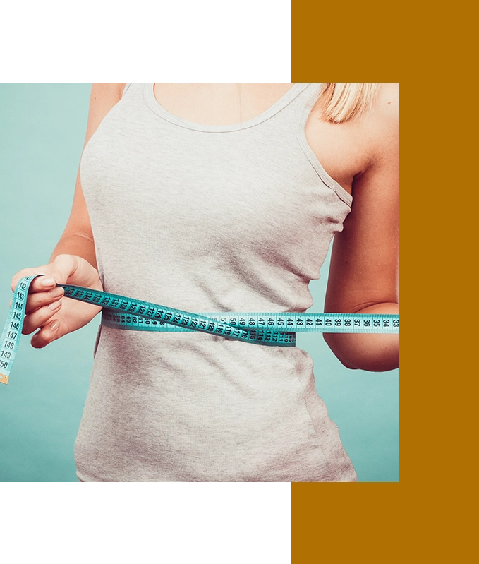 A person in a gray tank top holds a blue measuring tape around their waist, contemplating hypnosis for weight loss as a potential path to achieving their fitness goals.