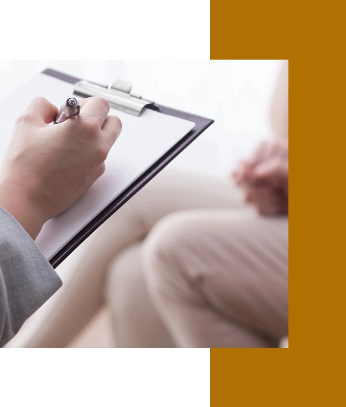 A person writing on a clipboard sits across from another with hands clasped, illustrating the calm, focused atmosphere typical of hypnosis services in Hartsville.